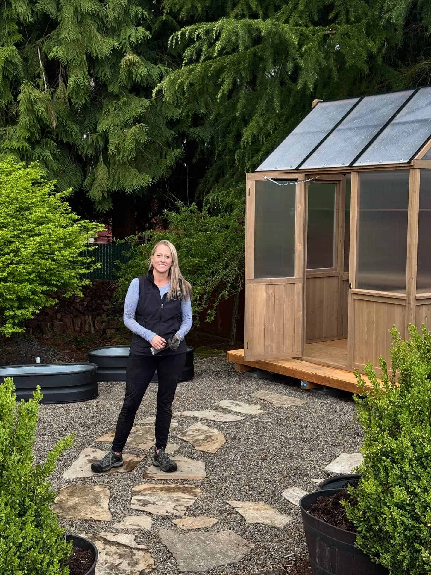 Justina, creator of More Ahead, standing outdoors near a garden studio