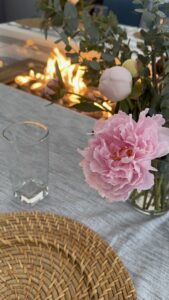Outdoor dinner club table set under a tent with pink flowers and candlelight for a Great American Road Trip themed dinner party.