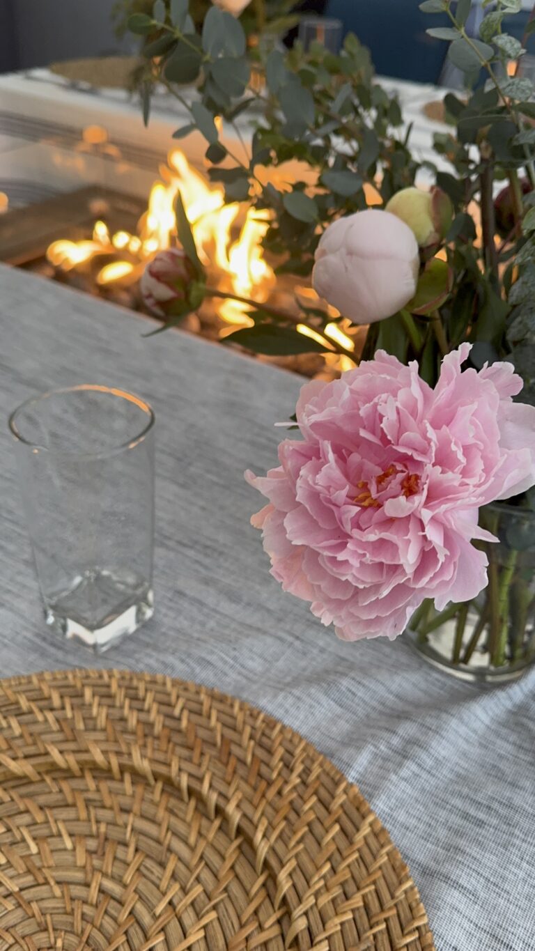 Outdoor dinner club table set under a tent with pink flowers and candlelight for a Great American Road Trip themed dinner party.