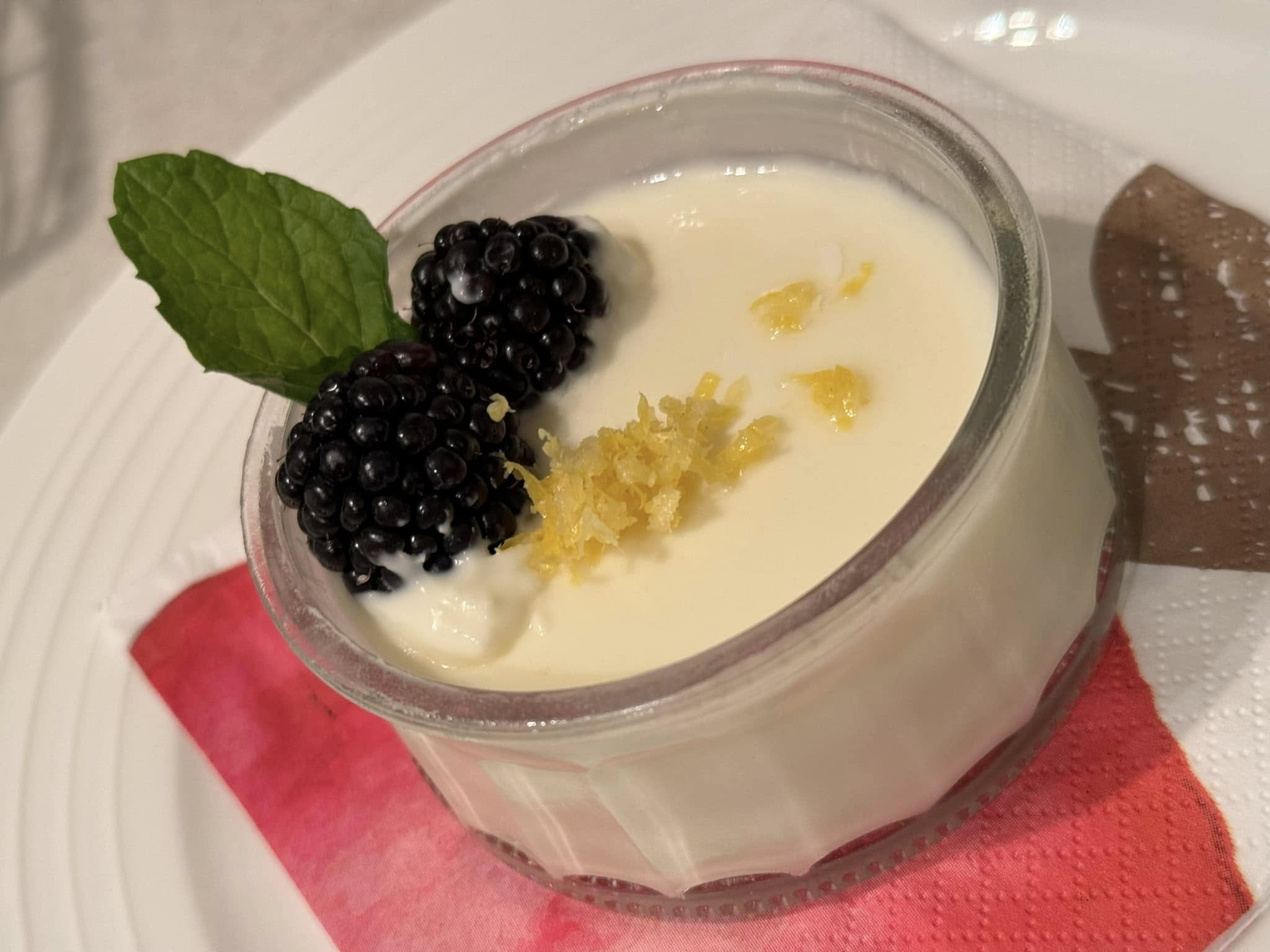 Individual lemon posset desserts garnished with lemon and fresh berries